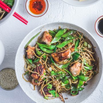 Soba noodles with salmon, snow peas in white bowl