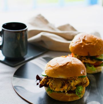Chicken omelette sandwich in burger bun with a coffee cup in the background