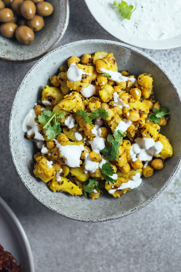Yellow coloured potatoes and chickpeas served in blue bowl