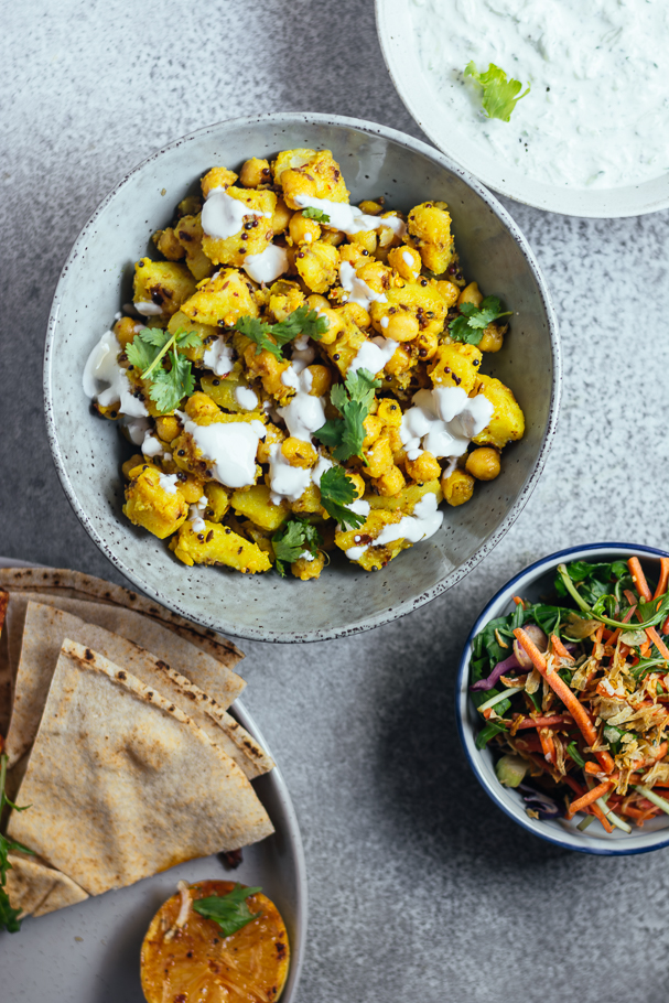Yellow coloured potatoes and chickpeas served in blue bowl