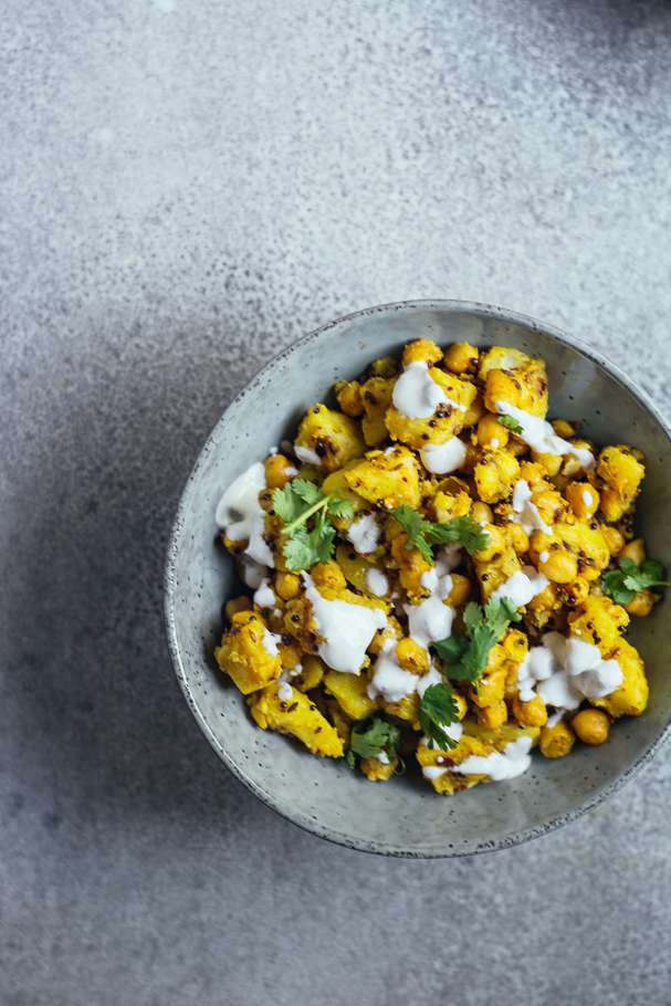 Yellow coloured potatoes and chickpeas served in blue bowl