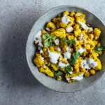 Yellow coloured potatoes and chickpeas served in blue bowl