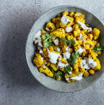 Yellow coloured potatoes and chickpeas served in blue bowl