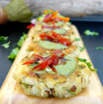 Indian style potato patties garnished with mint chutney served on wooden board