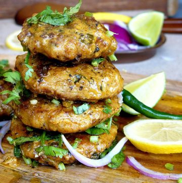 A stack of four chicken kebabs with lemon wedges on the side