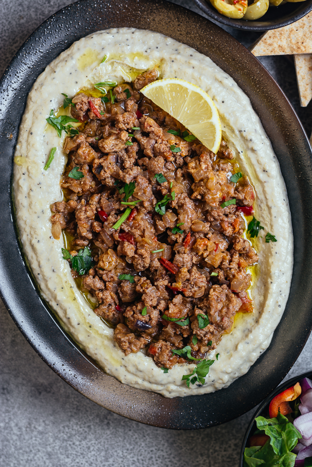 Brinjal dip topped with minced lamb served in oval black plate