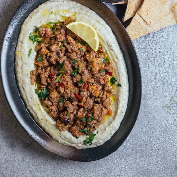 Brinjal dip topped with minced lamb served in oval black plate