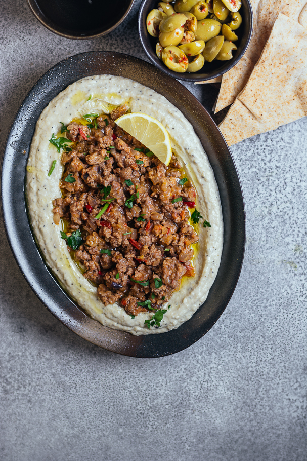 Brinjal dip topped with minced lamb served in oval black plate