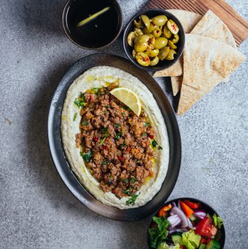 Brinjal dip topped with minced lamb served in oval black plate