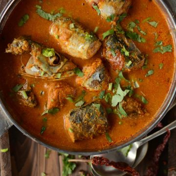Indian fish curry in bowl with dry red chillies on the side