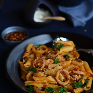 Pasta with squid in roasted tomato sauce served on black plate