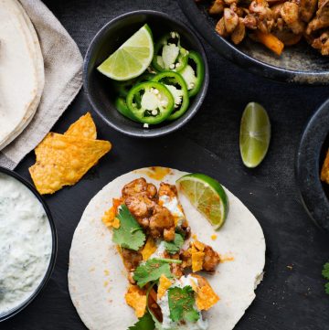 Chicken fajita taco with slices of lime, jalapeno on the side