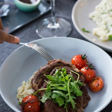 Steak with mashed potatoes and cherry tomatoes served in blue bowl