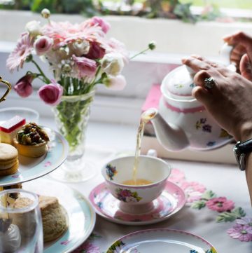 Hand pouring tea from pot into cup