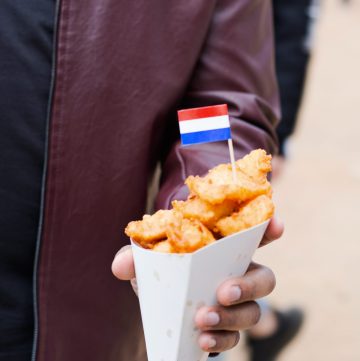 Hand holding fried nuggets in paper cone