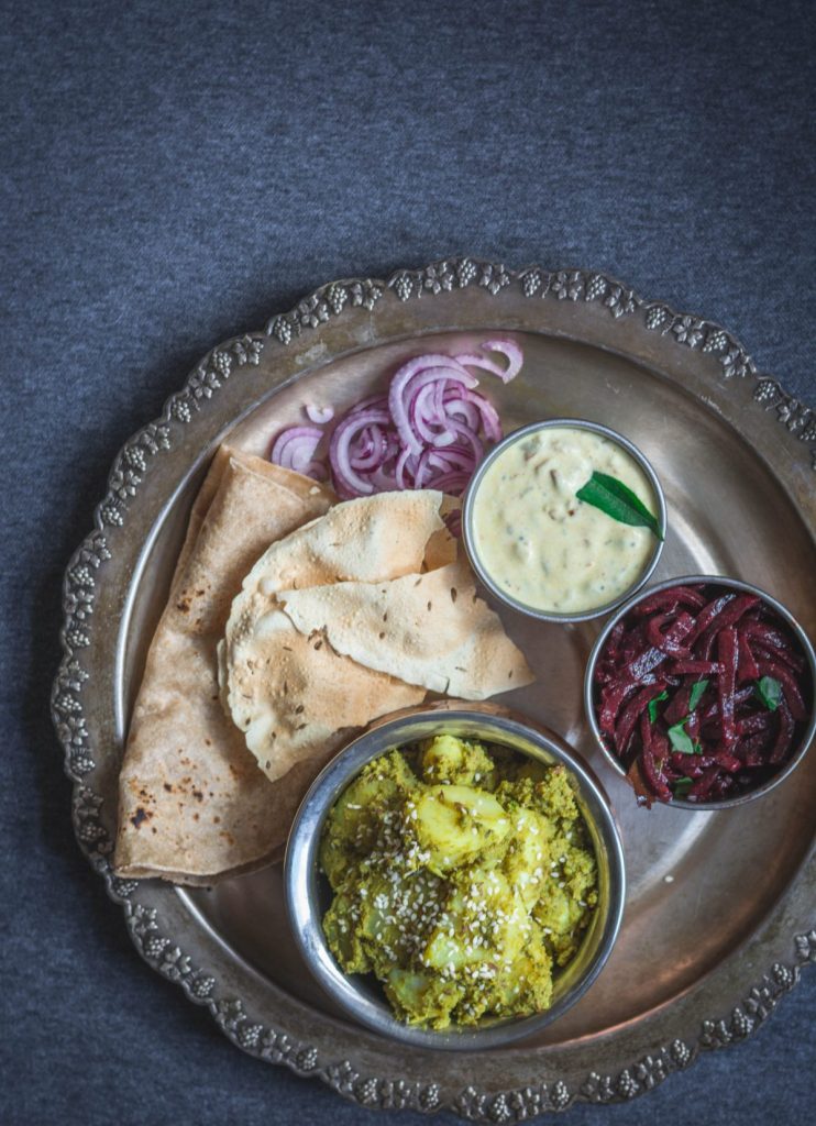 A round platter of different Indian dishes in small bowls