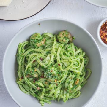 a bowl of pasta with pesto and prawns