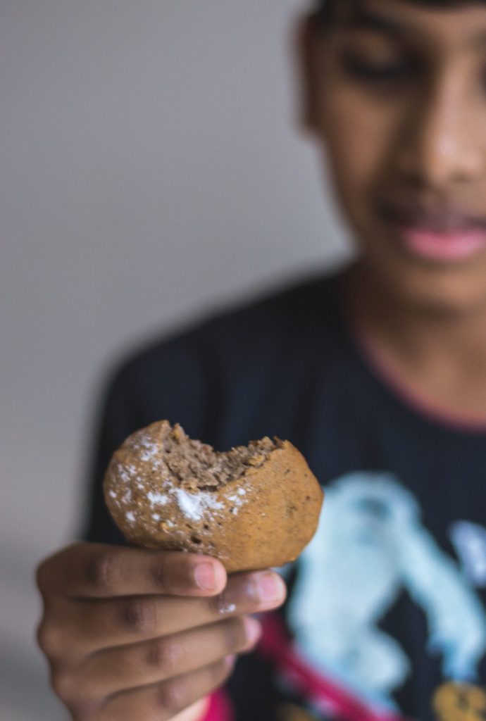 boy holding a half bitten banana chocolate cookie