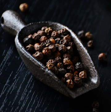black peppercorns in black spoon