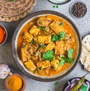 Indian paneer curry in a large bowl with accompaniments on the side