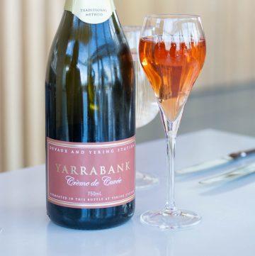 sparkling rose in a glass alongside wine bottle